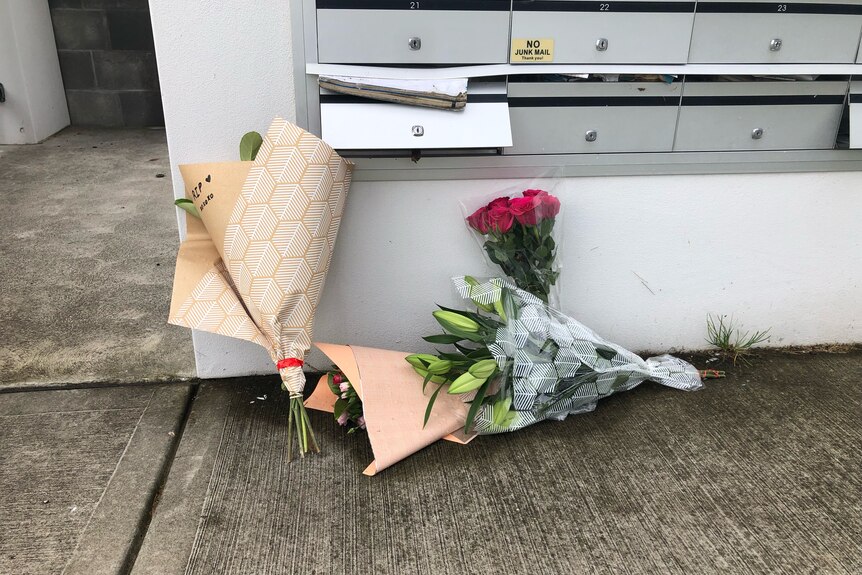 Bunches of flowers laid against an apartment complex letterbox