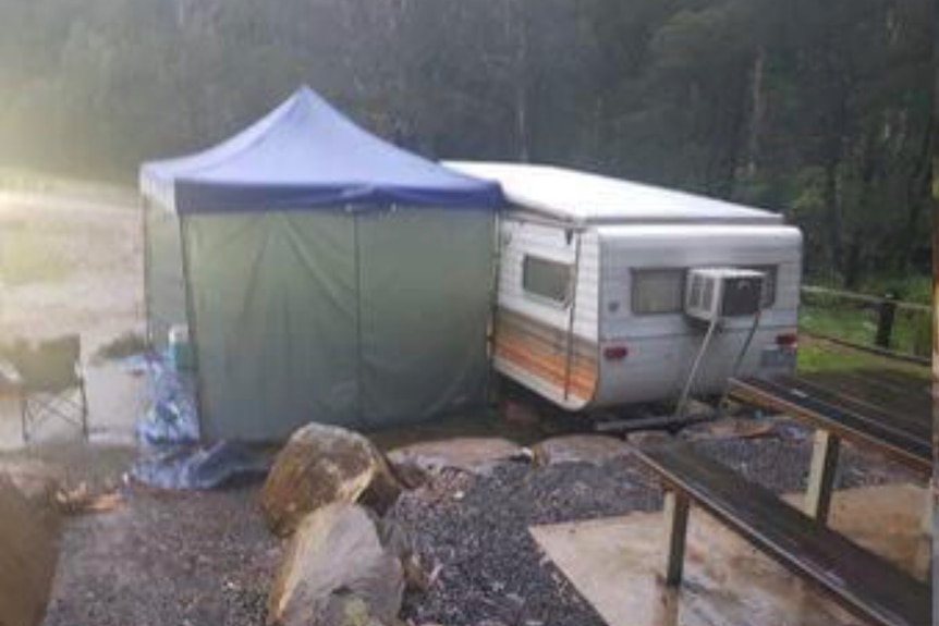 A blurry picture of a rainy looking campsite, featuring a caravan and an annex.
