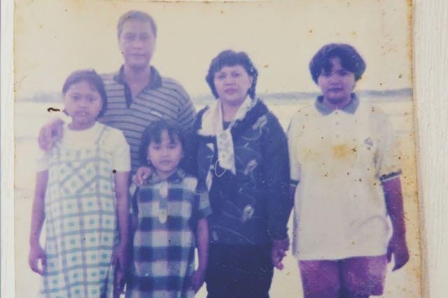 A black and white photo of Dea Winnie Pertiwi standing her sisters and parents.