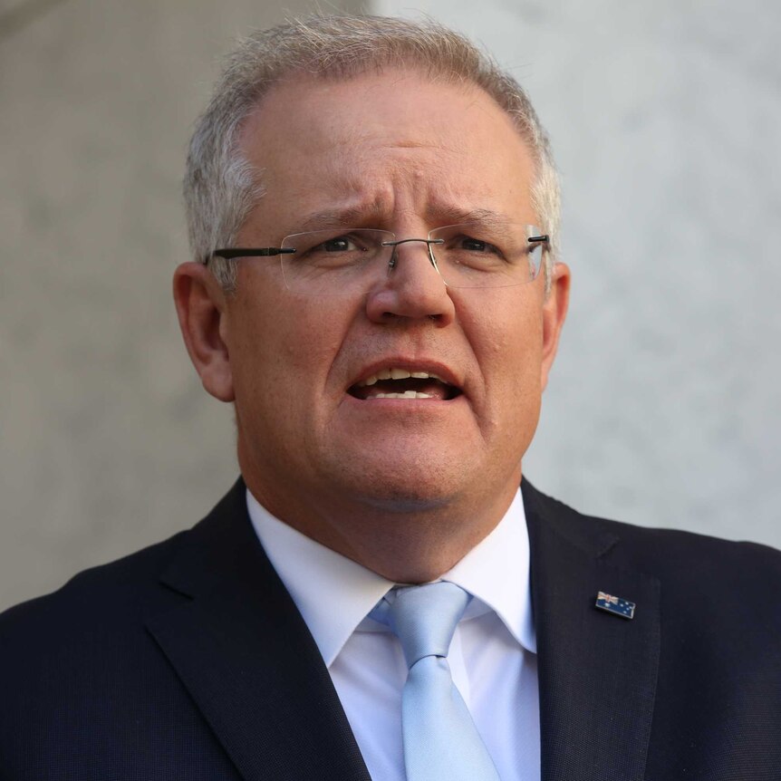Close up of the Prime Minister mid-sentence wearing a suit with a blue tie and an Australian flag lapel pin.