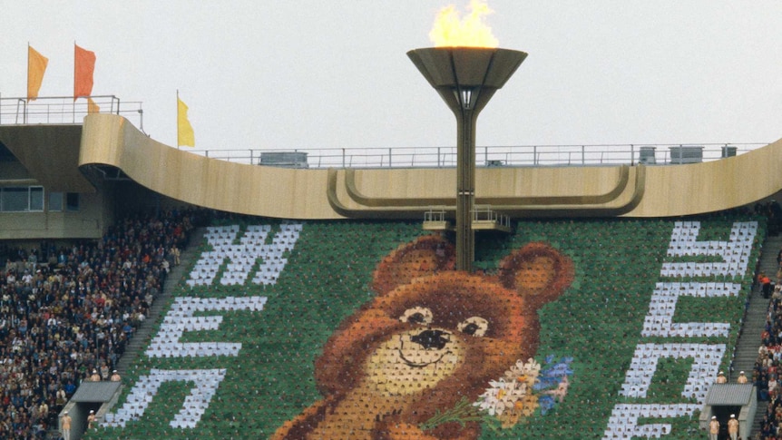 Olympic torch and the 1980 Russian Olympic mascot, a brown bear, Misha.