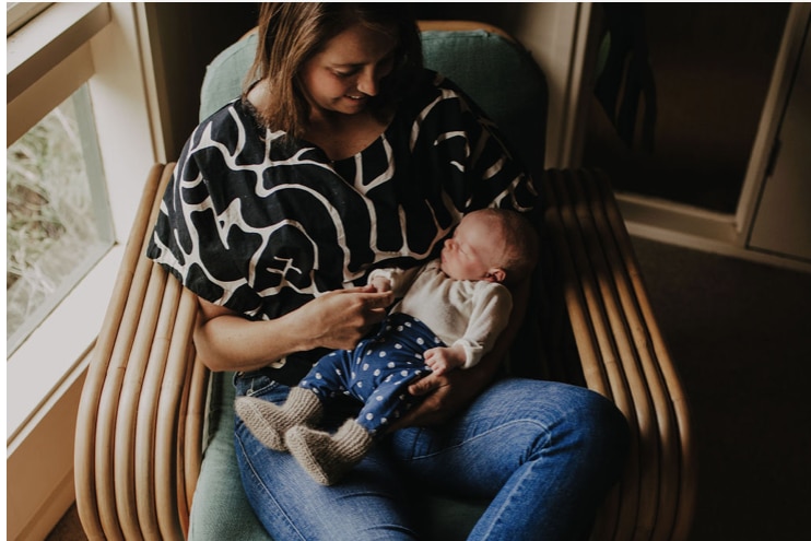 A woman smiles down at her newborn son