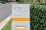 The driveway to an aged care village with the sign Lynden Aged Care at the entry in white, black and yellow.