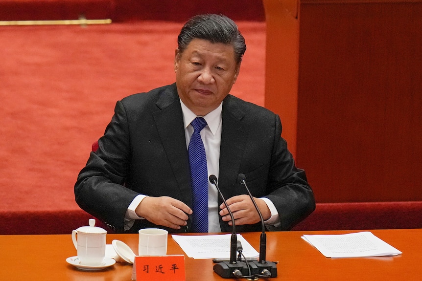 Xi Jinping sits down before speaking in the Great Hall of the People.