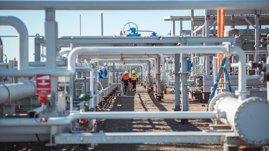 Two men walk through gas pipes