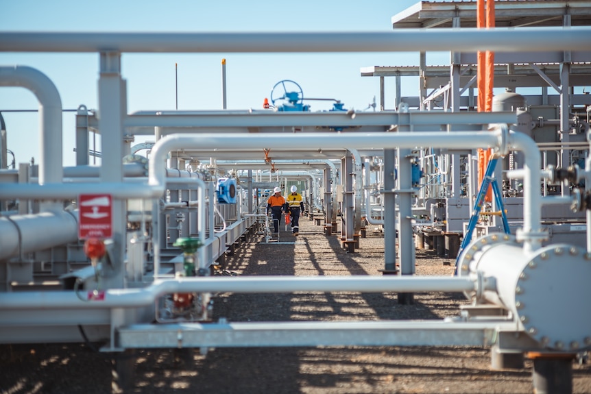 Two men walk through gas pipes