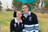 Two young people wearing school uniforms, who have bright blue hair. 