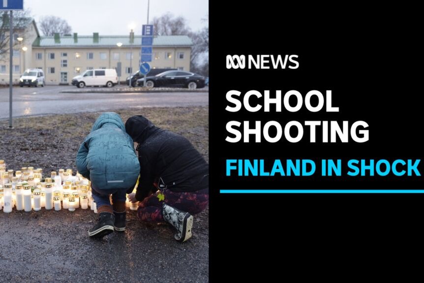 School Schooting, Finland In Shock: Mother and child wearing warm clothes add candle to vigil outside school.