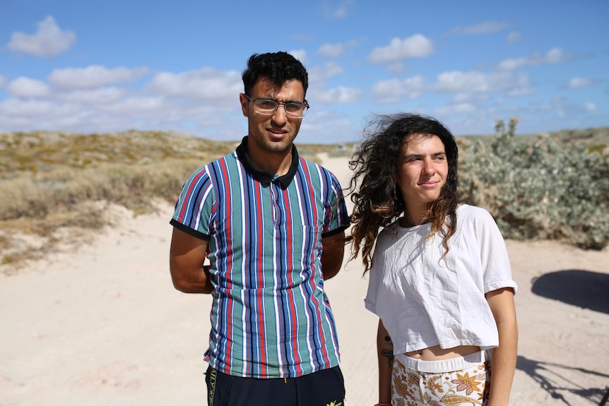 A photo of two Dutch travellers in front of sand dunes.