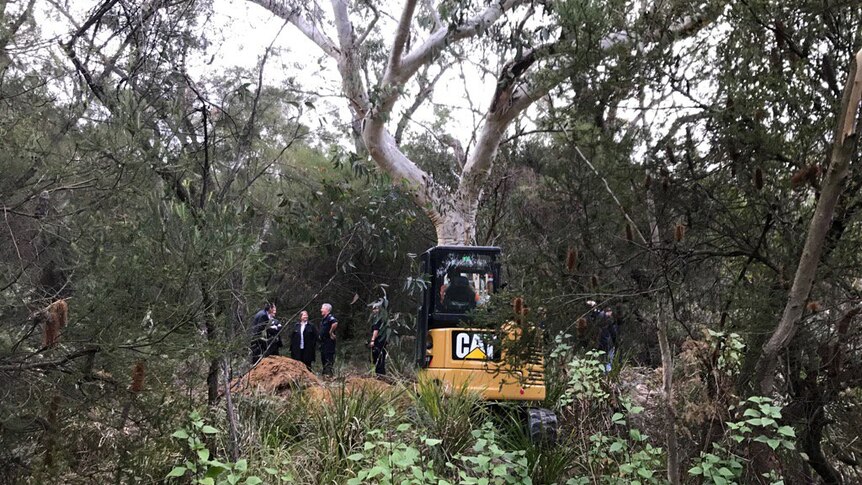 A digger and police officers in bushland.