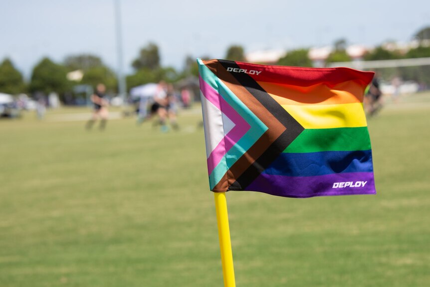 A colourful pride flag displayed on a football field. 