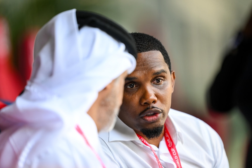 Samuel Eto'o speaks to a man in Qatari clothing at the FIFA World Cup.