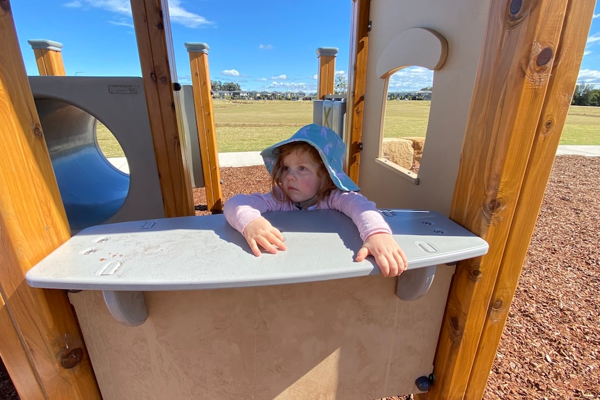 Three-year-old River Morpeth plays behind a pretend shop counter at a playground in Blacktown.