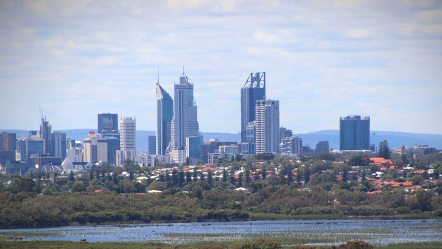 Perth city skyline viewed from a hill with a lake in the foreground