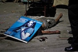 Police investigators used a poster to cover the body of an unidentified male victim shot in Quezon City.