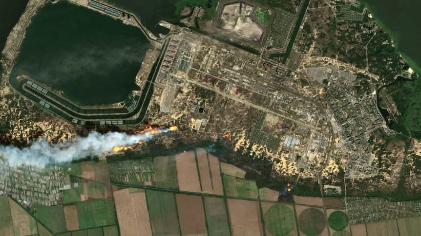 Satellite image shows fire and smoke near power plant.