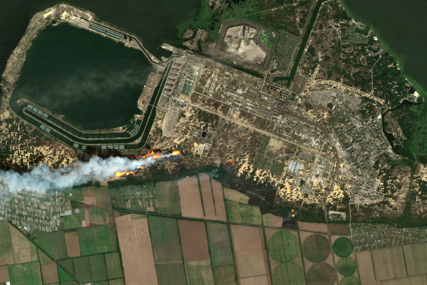 Satellite image shows fire and smoke near power plant.