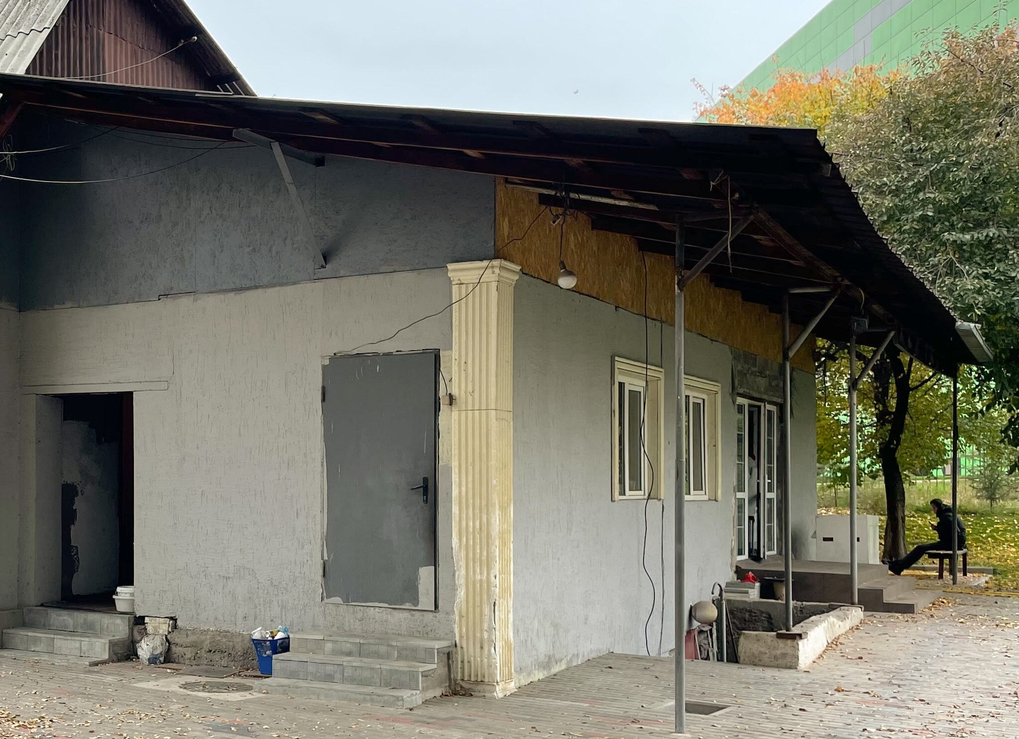 A house painted grey with a man sitting on a chair in the background.
