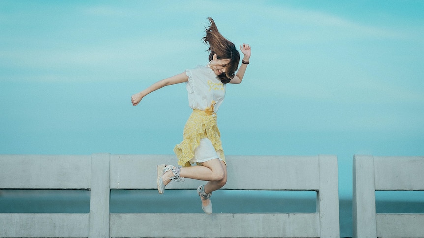 Woman jumping for joy in front of a body of water