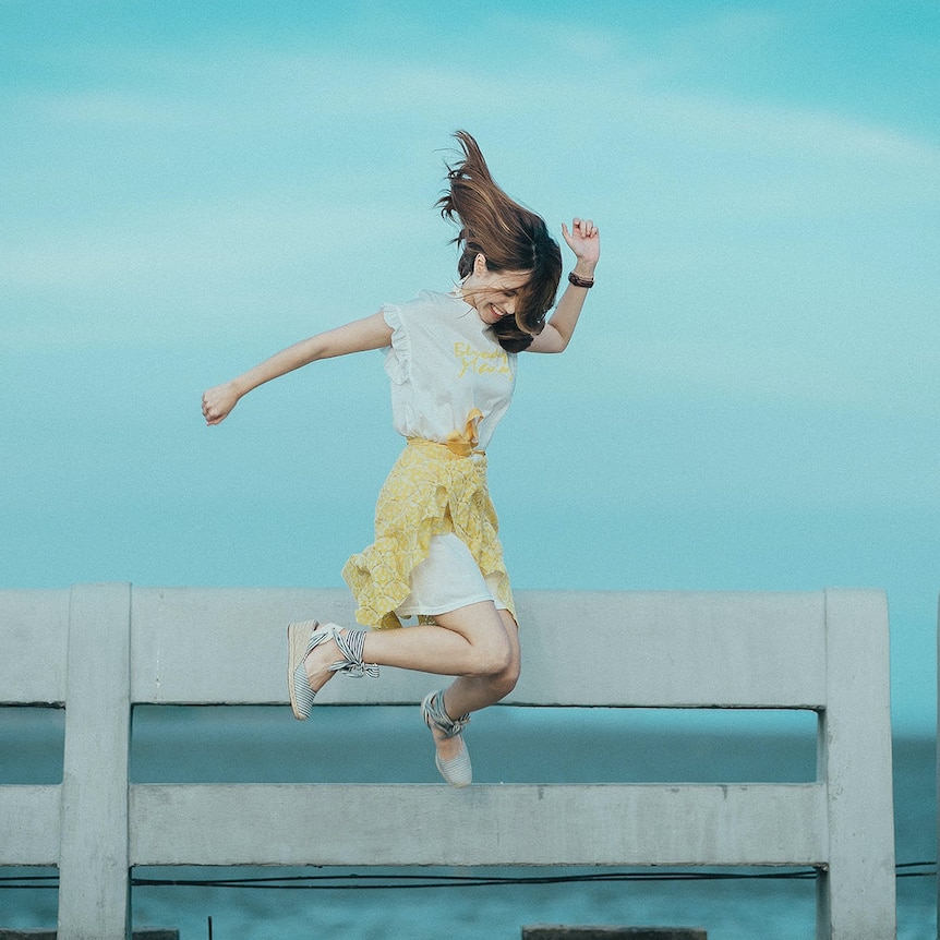 Woman jumping for joy in front of a body of water