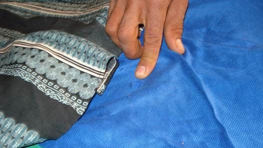 A close-up of a finger pointing to blue jeans and a shirt.