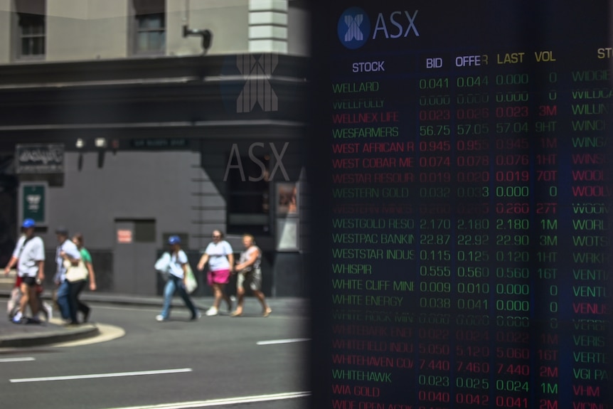 Four people walk along a footpath in front of the ASX building on a sunny day.