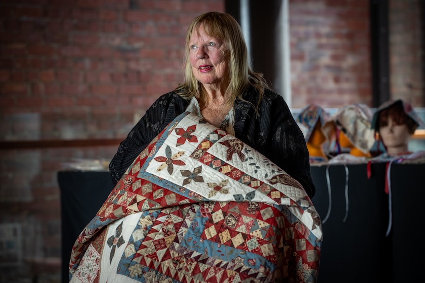 A woman holding a quilt.