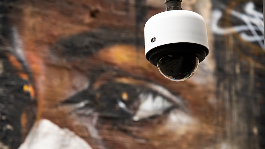 Image of a CCTV camera in front of street art of Aboriginal girl