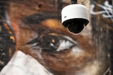 Image of a CCTV camera in front of street art of Aboriginal girl