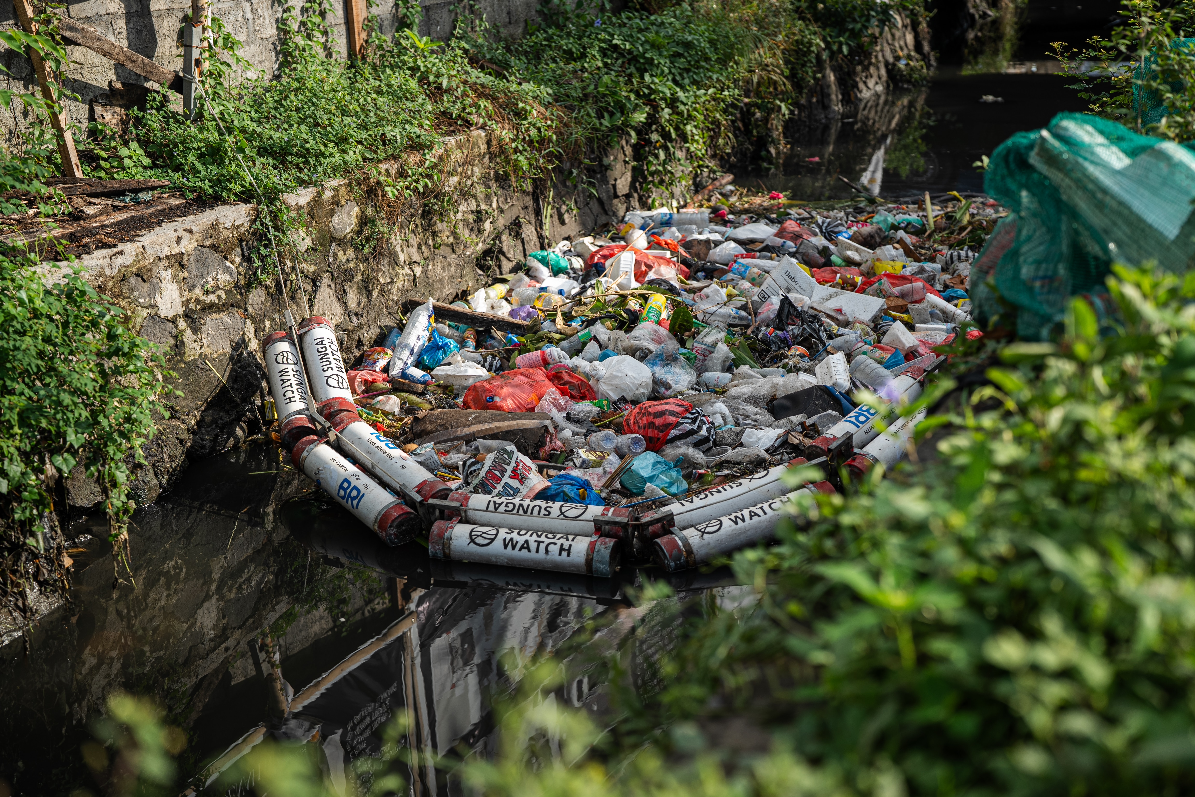 A trash barrier prevents rubbish from filtering downstream in a river in Bali's Denpasar.