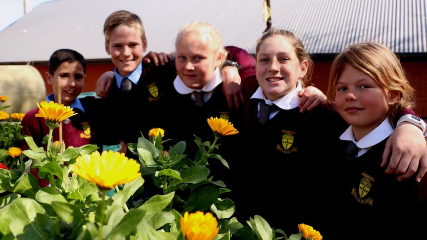 Five students stand behind a flower bed at St  Raphaels in Cowra.