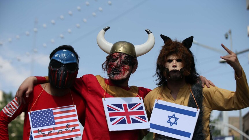 Three men in masks pose for a photo, wearing a US, UK and Israeli flag around each of their necks.