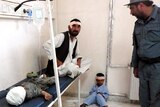 An Afghan policeman looks at a wounded man and children after a suicide attack in Khost city.