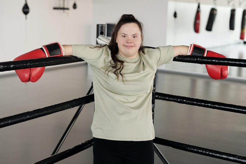 A young woman with Down syndrome standing in a boxing ring.