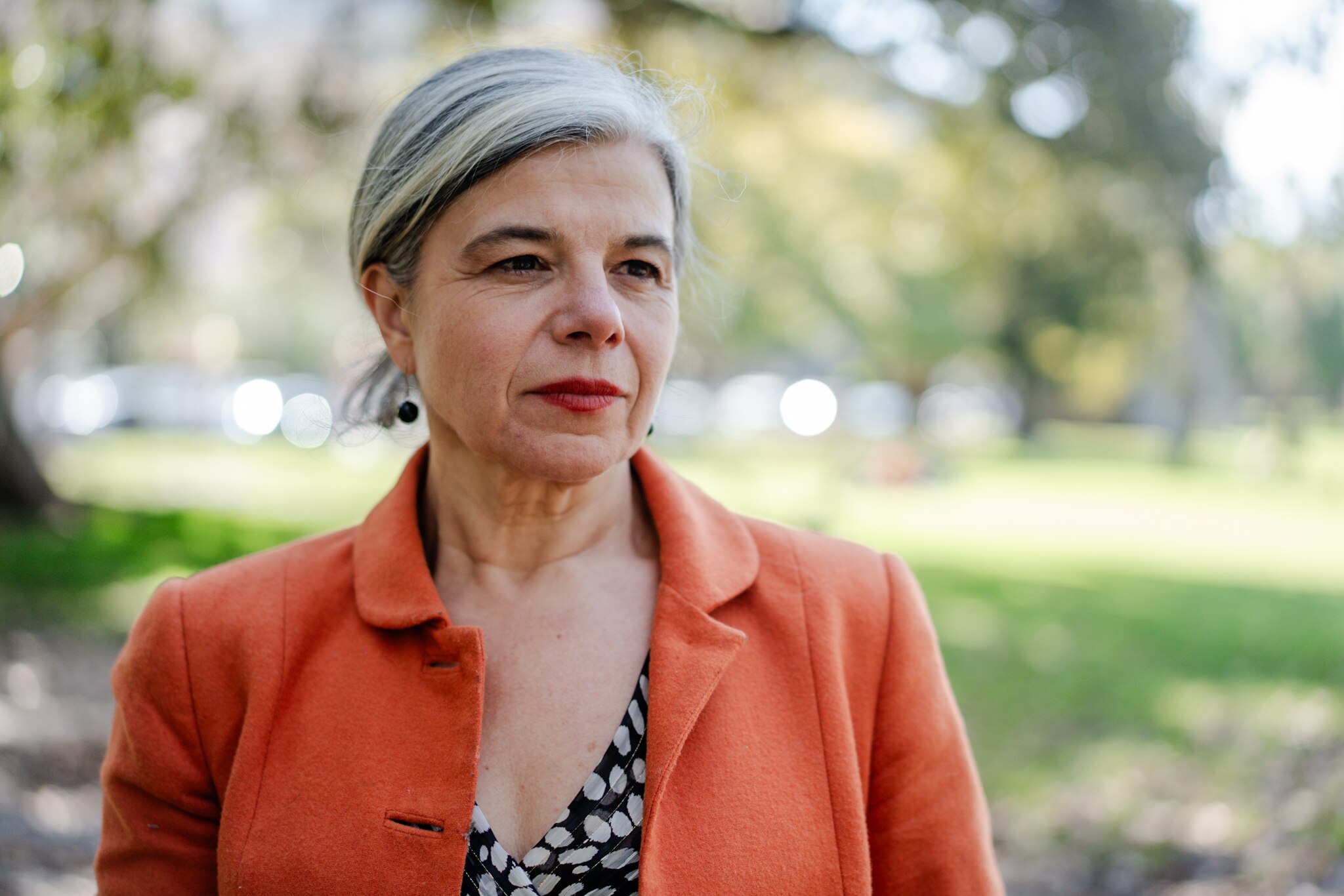 uma mulher vestida com uma jaqueta laranja e uma camisa de bolinhas