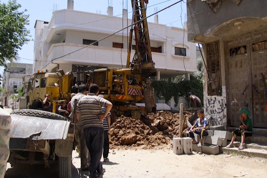 People watch as construction begins on Abdel Rahman's house, which is currently nothing but rubble.