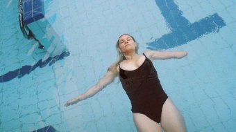 A woman floats on her back in a swimming pool.