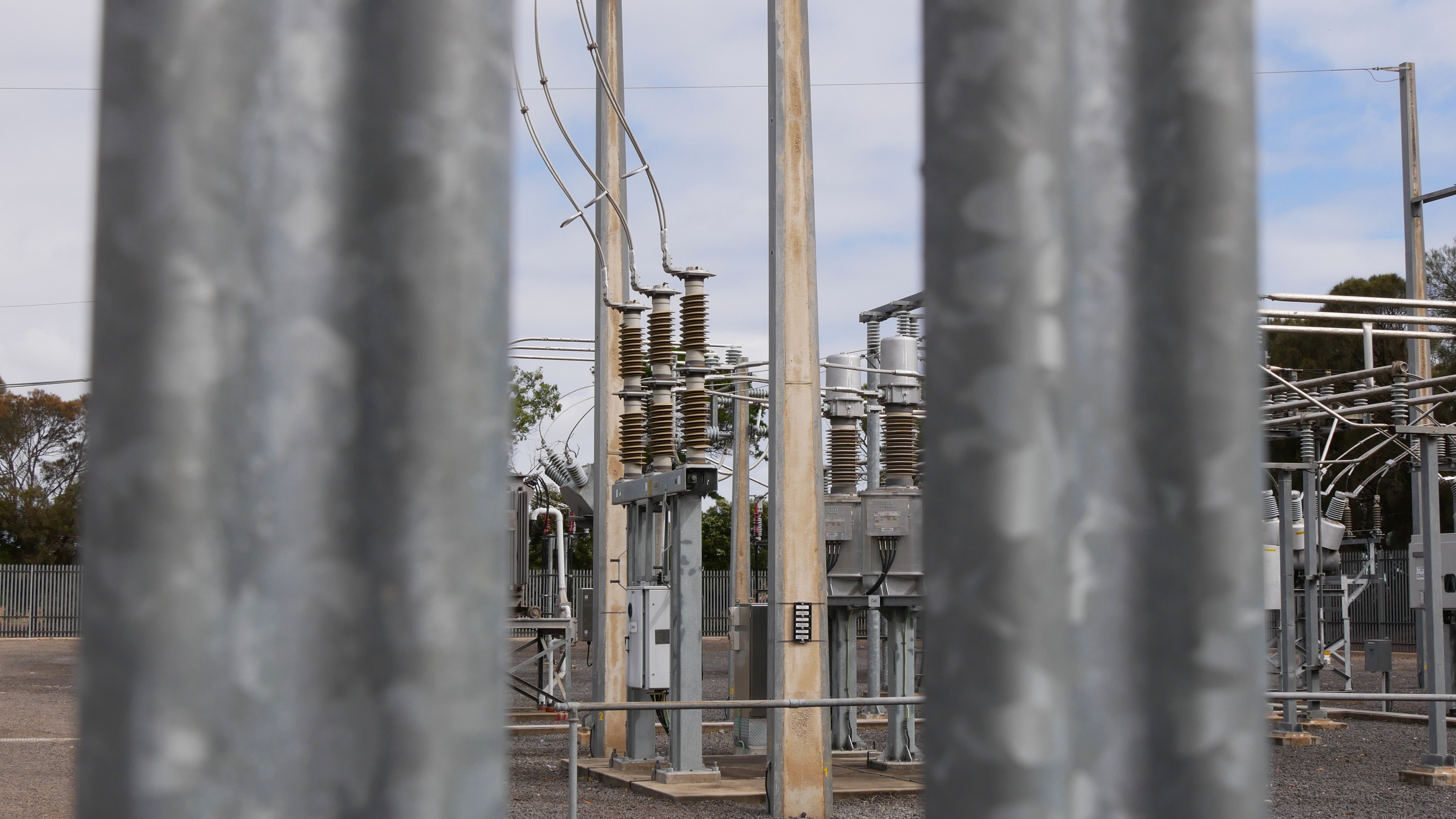 Транспортер высокого напряжения между двумя столбами на электрической подстанции.