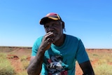 Eric Moora sits on Country in Balgo