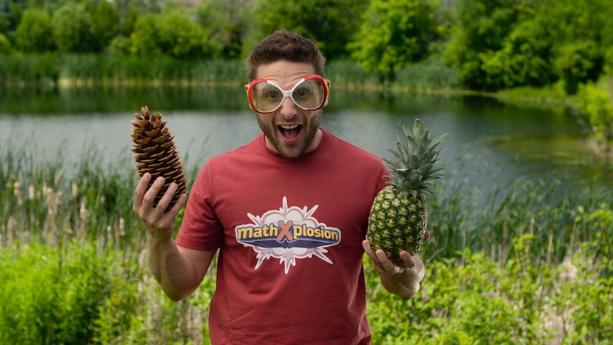 Man wears novelty glasses, holds pineapple and pine cone
