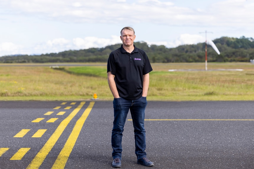 A man stands on an airport runway with his hands in his pockets