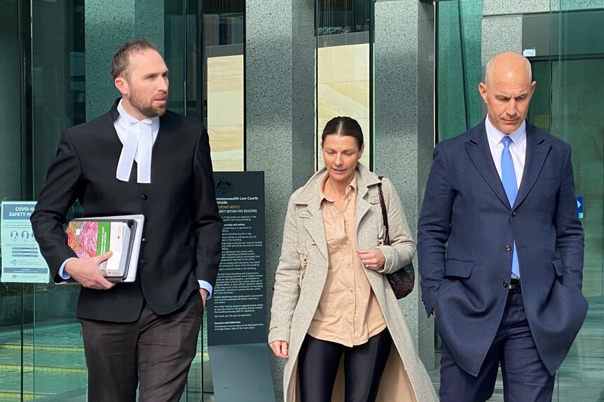 Two men and a woman walk outside a court building