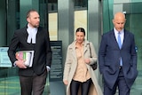 Two men and a woman walk outside a court building