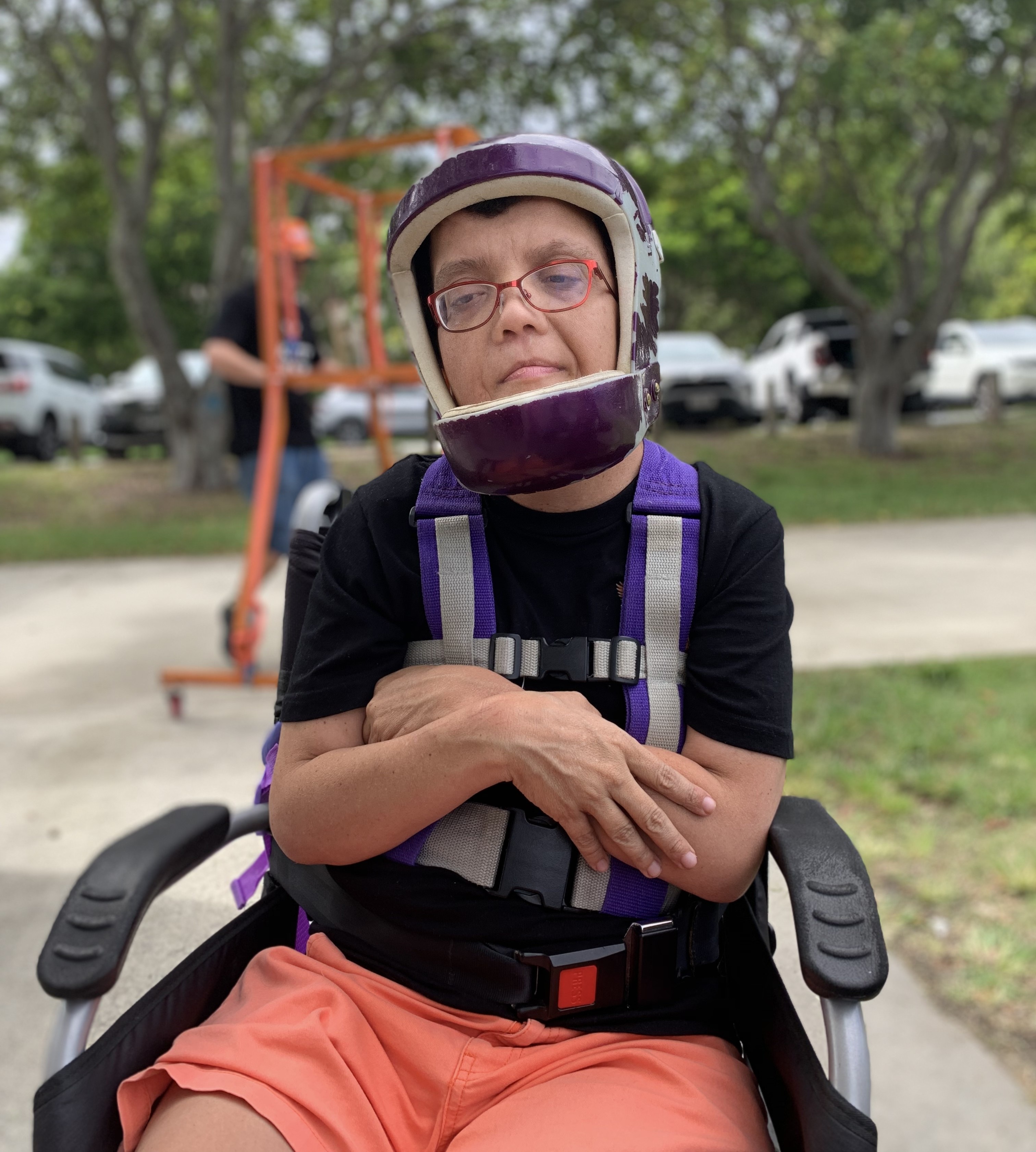 woman in a wheelchair, wearing a helmet.