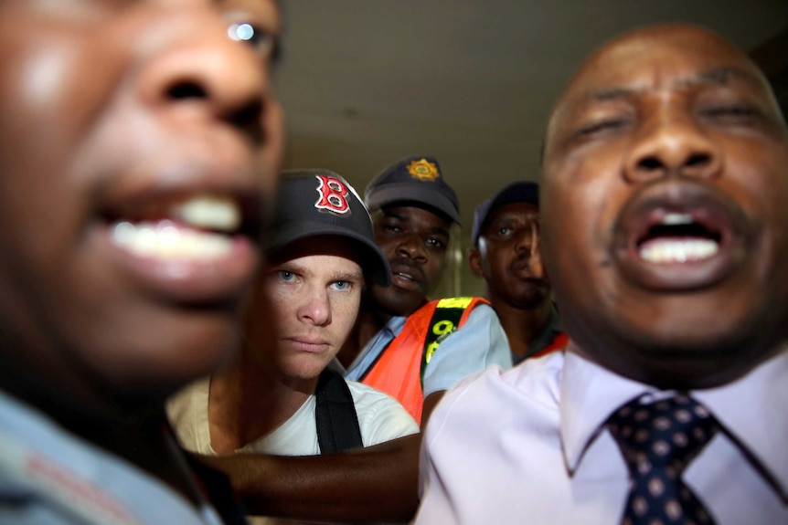 Steve Smith is escorted by a crowd of police officers