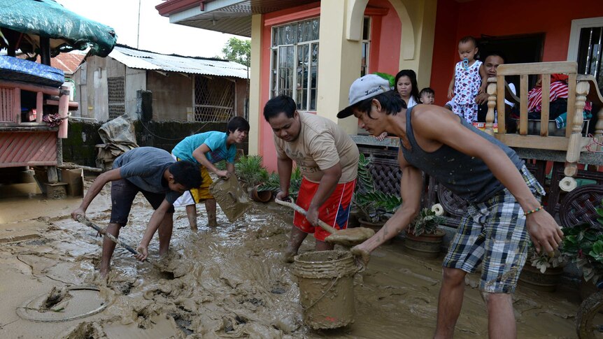 Residents remove mud near their house