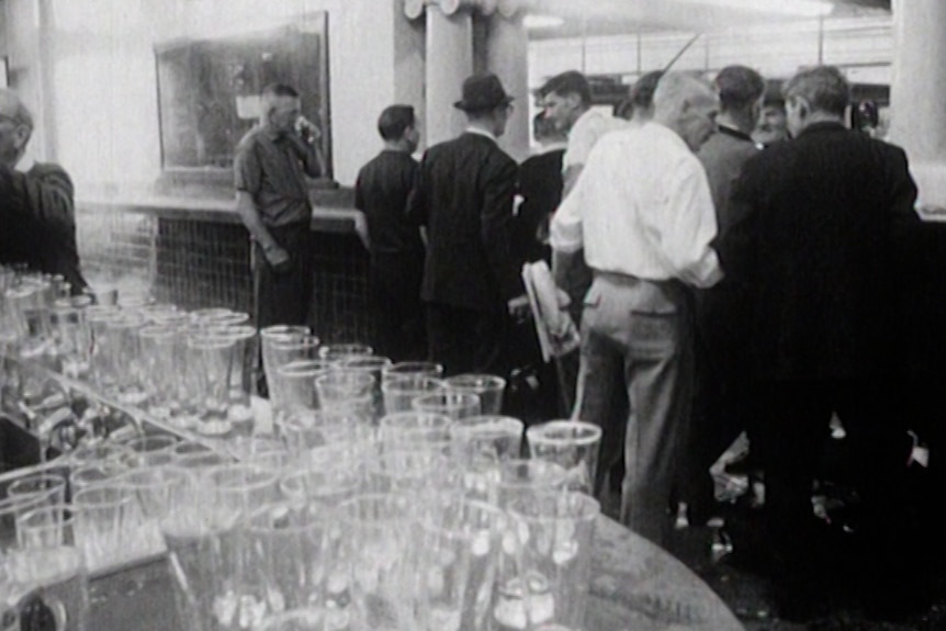 Men walk towards pub exit with multiple empty, dirty glasses left on the bar. 