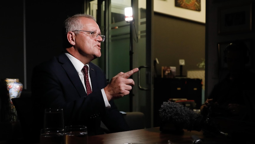 Scott Morrison gestures as he speaks to a camera while sitting in an office