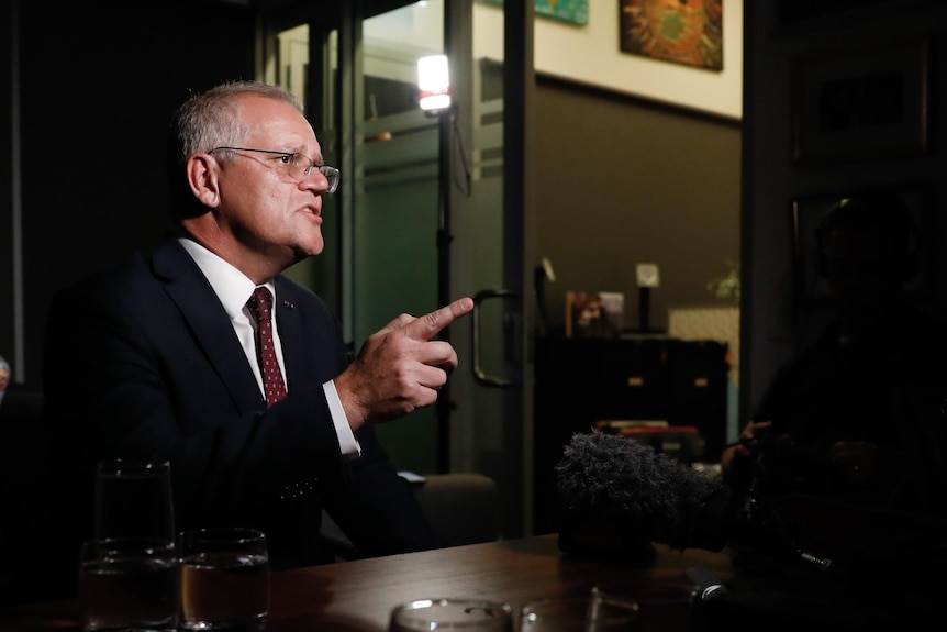 Scott Morrison gestures as he speaks to a camera while sitting in an office