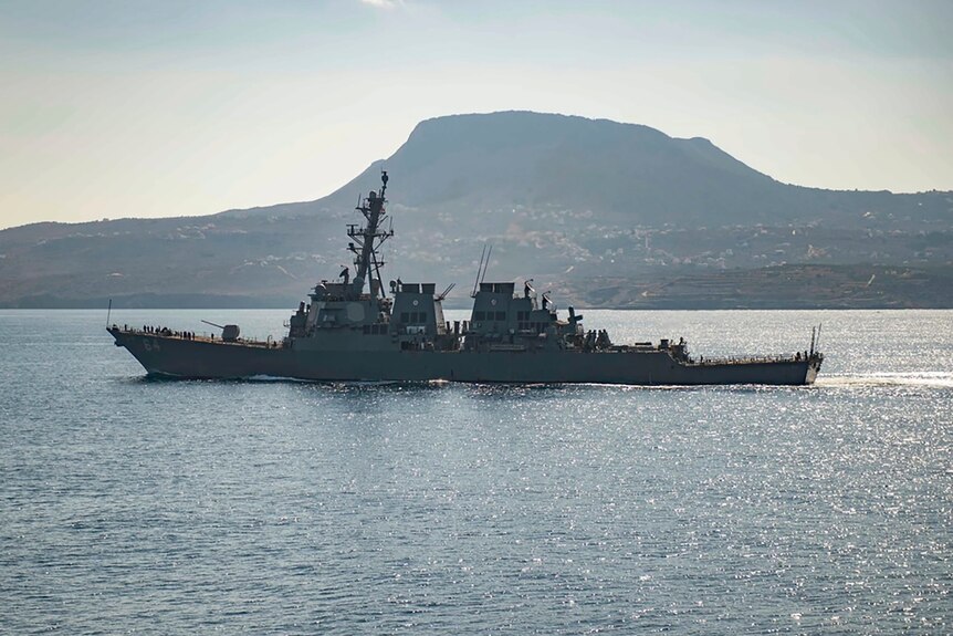 US warship in the sea as a mountain lies in the background 